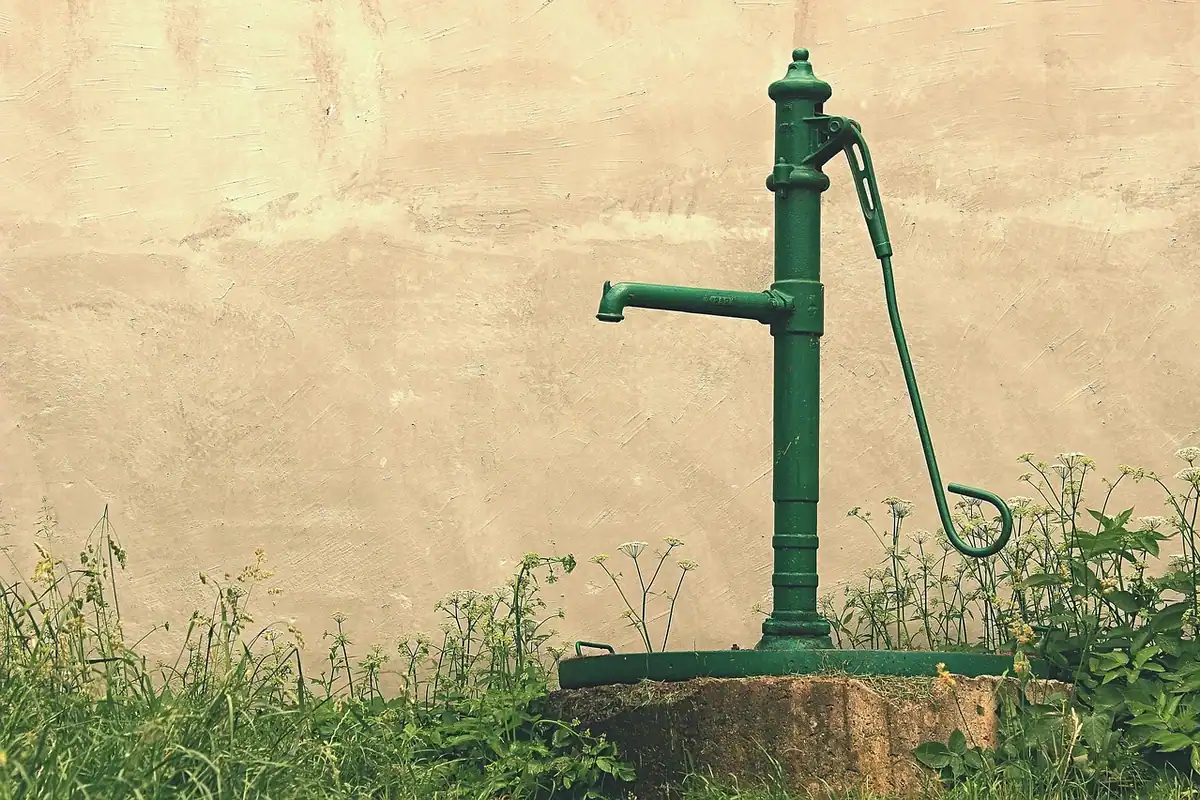 Pompă manuală veche din metal ruginit pentru apă, într-o grădină de la țară, într-o dimineață rece