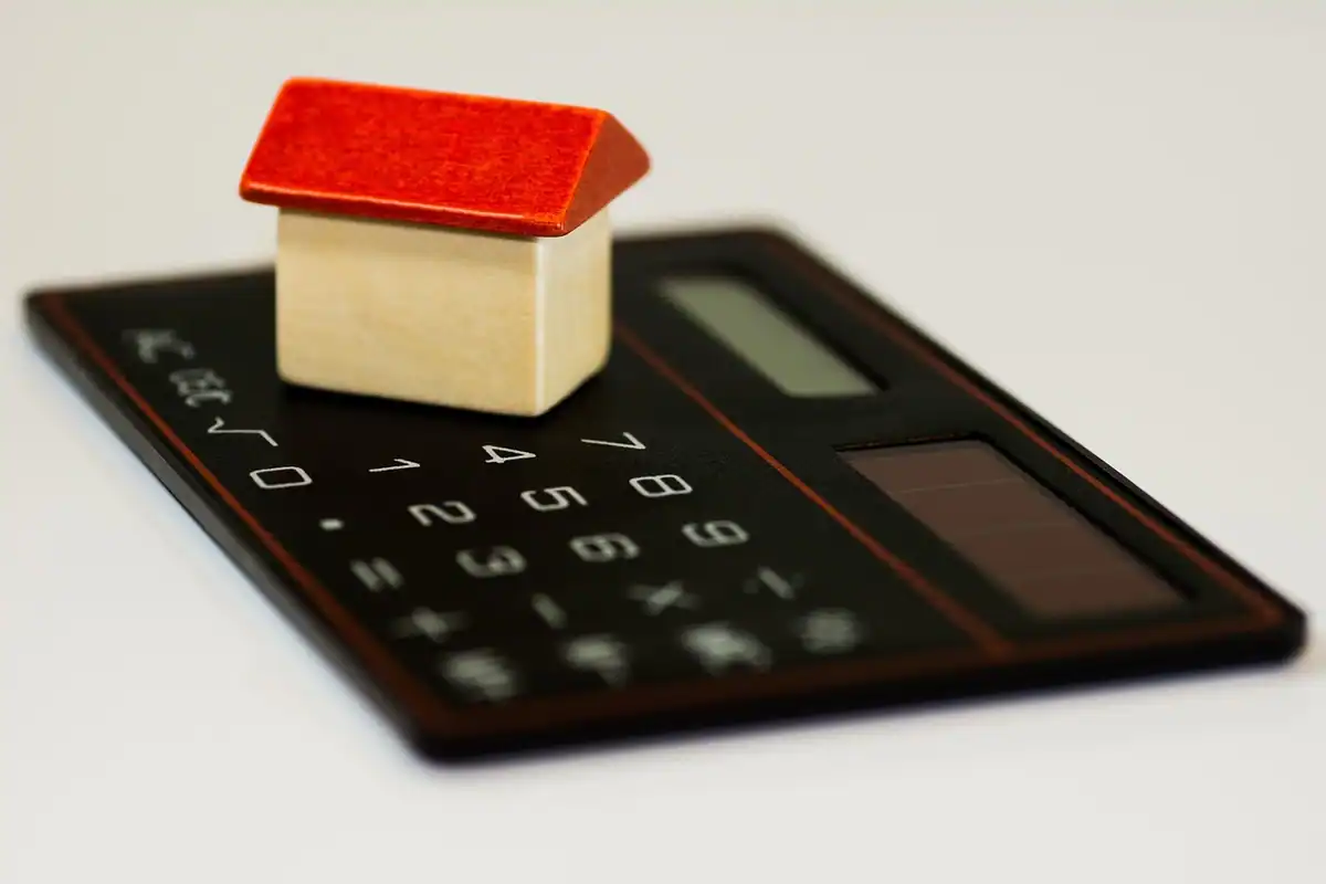 Căsuță de lemn așezată pe un calculator, simbol pentru bugetul construcției