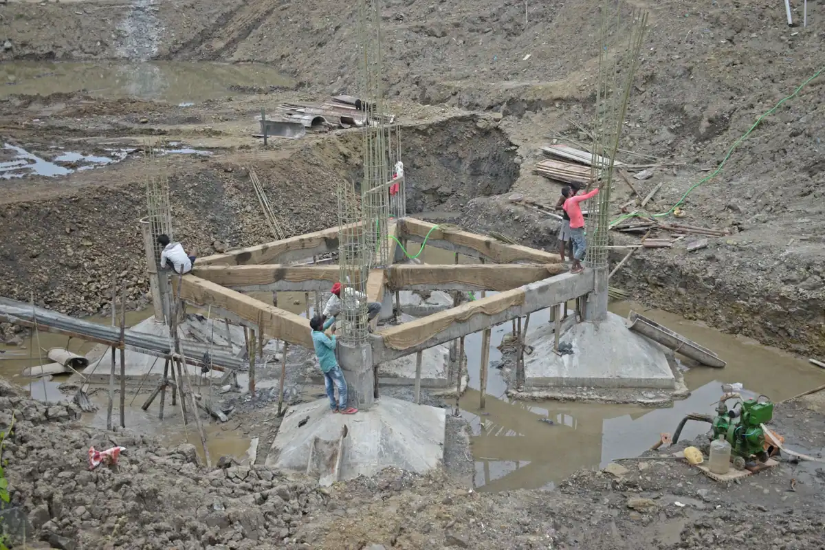 Muncitori armează o cofrare de lemn într-o groapă, la o structură din beton