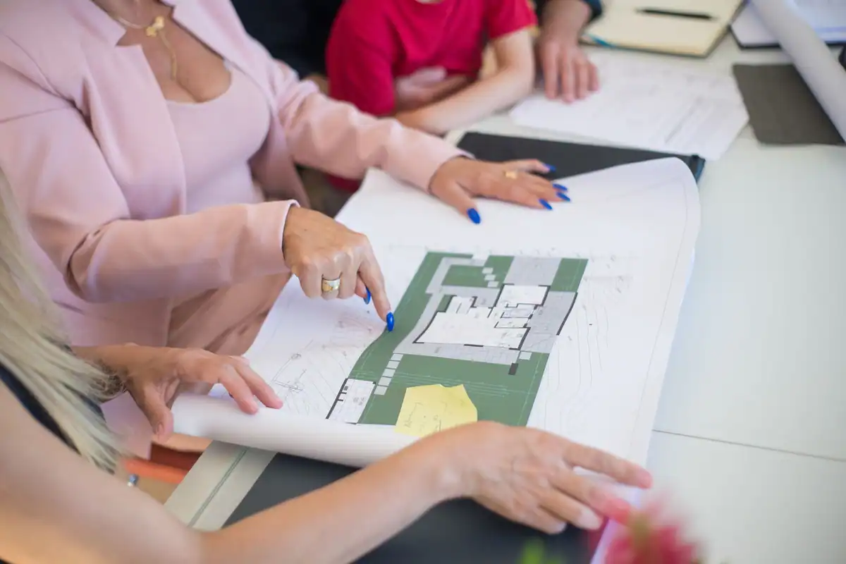 Mai multe persoane studiază împreună un plan de casă cu amenajarea terenului