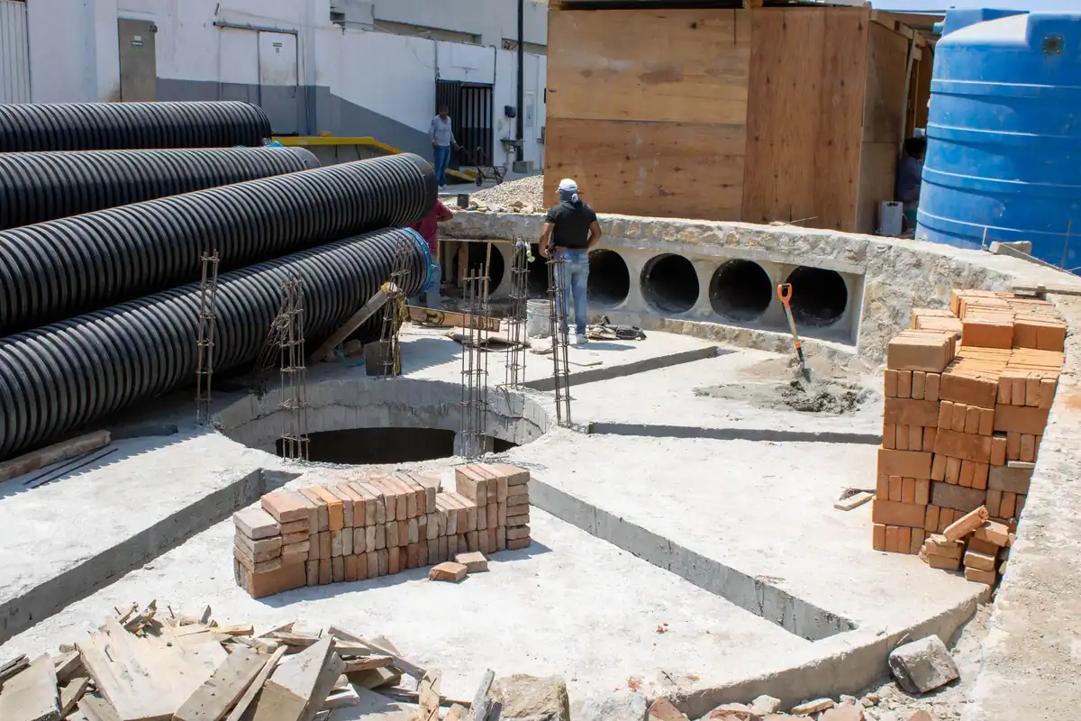 Tuburi de canalizare și cămin de beton în lucru, lângă o groapă pentru fosă