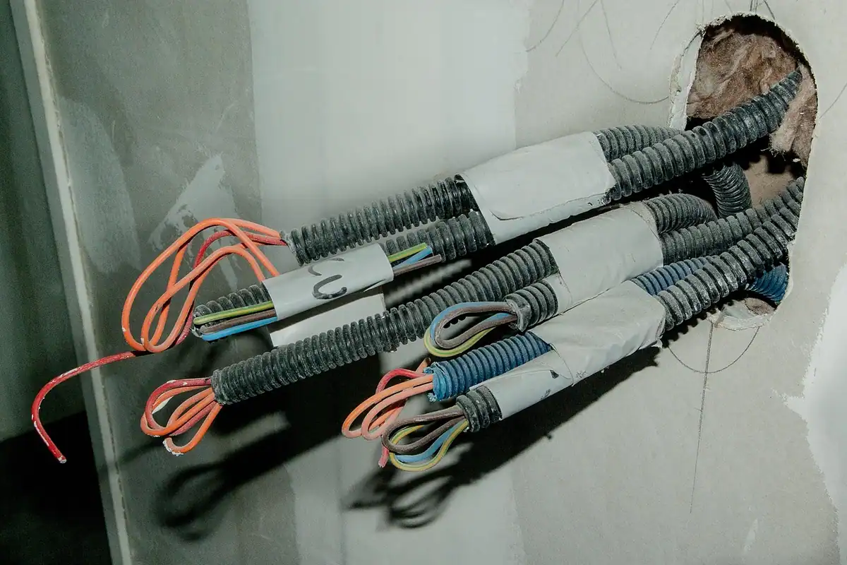 Tuburi flexibile cu fire colorate ieșind dintr-un perete, pentru instalația electrică