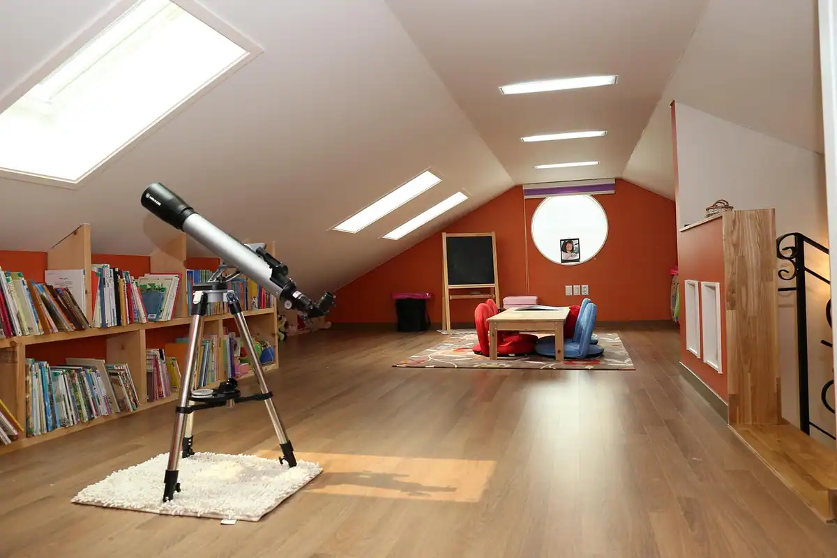 Mansardă amenajată ca spațiu de joacă, cu rafturi de cărți și telescop