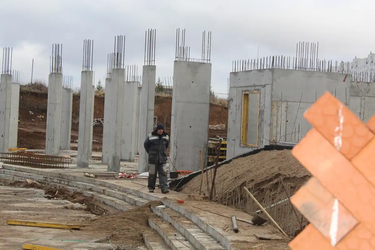 Clădire în construcție pe un șantier, cu fundație și structură în lucru