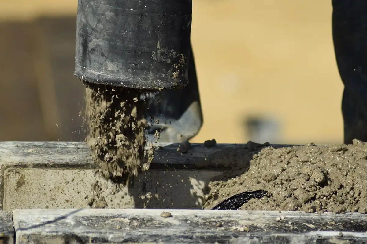 Pompă de beton care toarnă beton pe un șantier, cu muncitori în lucru