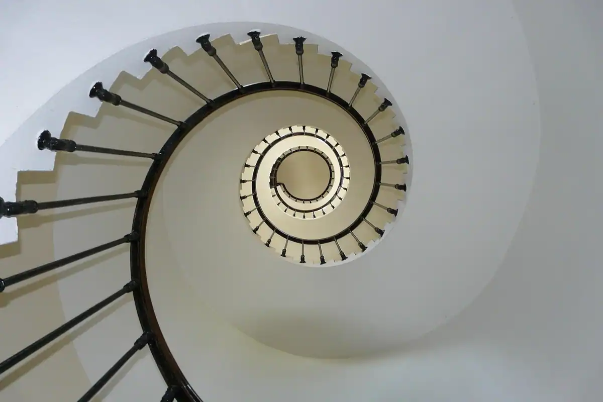 Scară interioară cu balustradă și trepte, fotografiată dinspre jos în sus, într-o clădire
