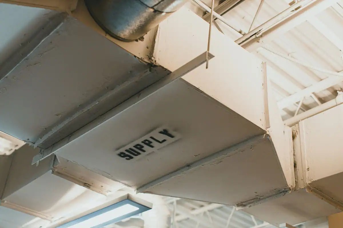 Conducte metalice de ventilație care se întretaie sub tavanul unei clădiri