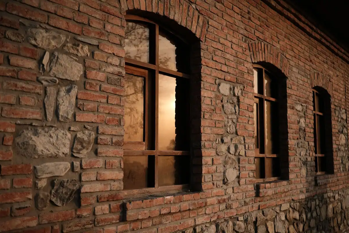 Zid de cărămidă și piatră cu ferestre arcuite, luminate din interior
